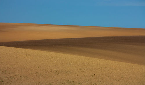 Scenic view of desert against clear blue sky