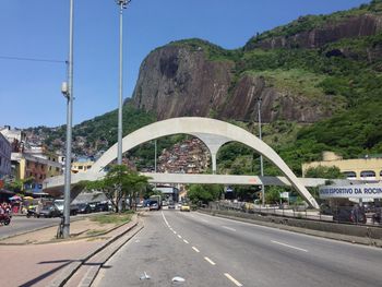 Road by arch bridge in city against sky