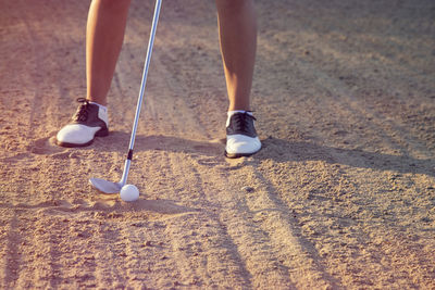 Low section of woman playing with ball on sand