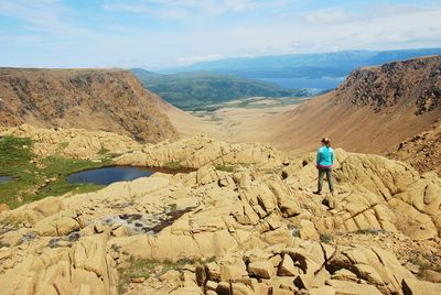 Rear view of a woman standing on rock formation in newfoundland