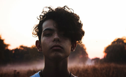 Close-up portrait of young man against sky during sunset
