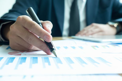 Midsection of man analyzing graphs on desk