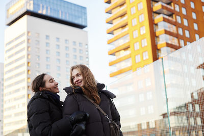 Smiling female couple standing in modern neighborhood