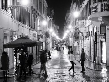 People on illuminated street in city