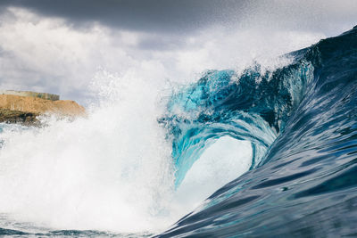 Close-up of sea wave splashing against blue sky