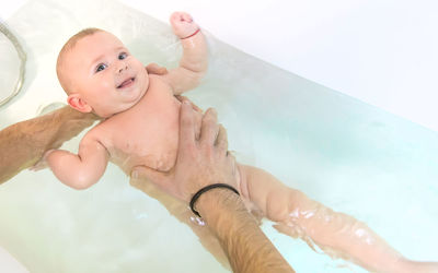 High angle view of shirtless boy swimming in bathtub