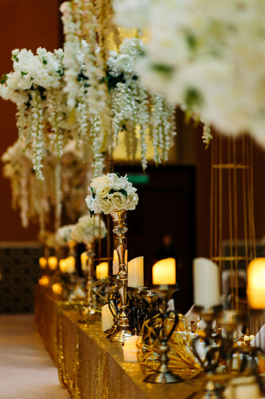 CLOSE-UP OF ILLUMINATED LAMP ON TABLE AGAINST WALL