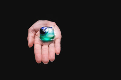 Close-up of hand holding electronic cigarette against black background