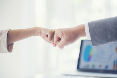 Cropped hands of business colleagues bumping fists in office