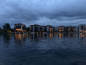 Buildings by river against sky