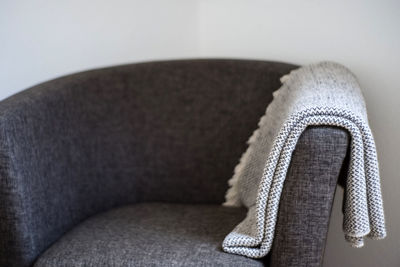 Close-up of shawl on armchair against wall at home