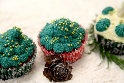 High angle view of christmas cupcakes with pine cone on snow