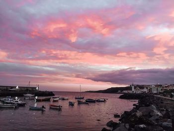 Boats moored at harbor against sky during sunset