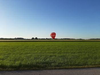 Hot air balloons on field against clear sky