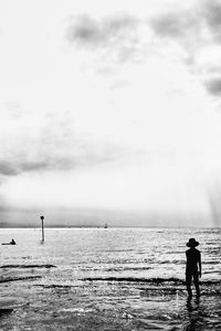 Rear view of men standing at beach against sky