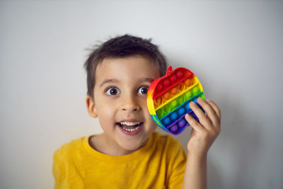 Boy in a yellow t-shirt plays a fashion game pop it in the form of a silicone apple