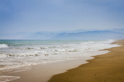 Scenic view of beach and sea with mountains against sky