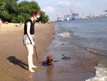Woman with dog on shore at beach