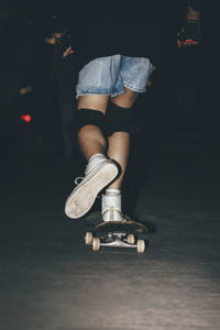 Woman skateboarding in park at night