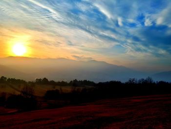 Scenic view of silhouette field against sky at sunset