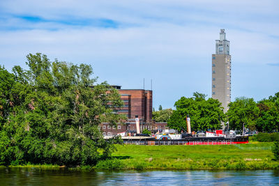 View of trees by river against buildings