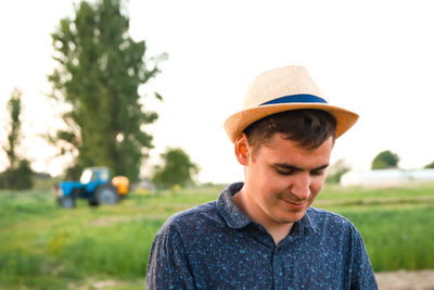 Farmer in hat working on field with greenhouse outdoor. portrait of young caucasian handsome happy