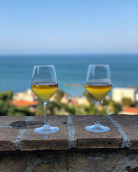 Wine glasses on beach against blue sky