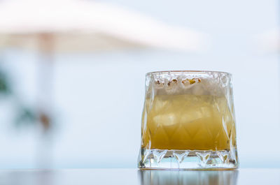 A glass of pineapple cocktail with blurred umbrella background for holiday and summer drink concept.