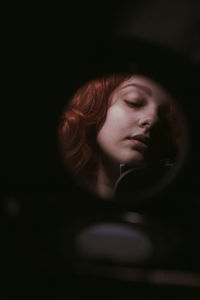 Close-up of mirror with reflection of young woman