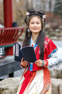 Portrait of young woman using digital tablet while standing outdoors