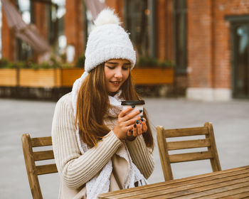 Young woman drinking coffee while sitting at outdoor cafe