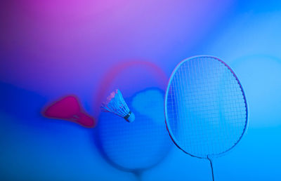 Close-up of badminton racket with shuttle cock pink background