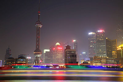 Light trails on huangpu river against illuminated city against sky