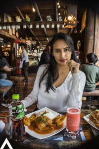 Portrait of young woman sitting at restaurant table