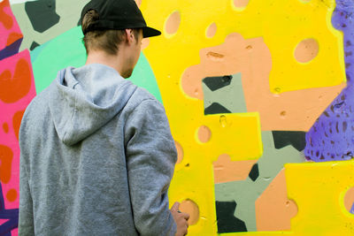 Rear view of man making graffiti on wall