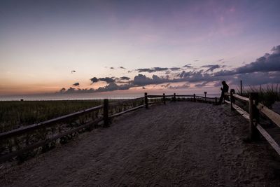 People on beach against sky during sunset