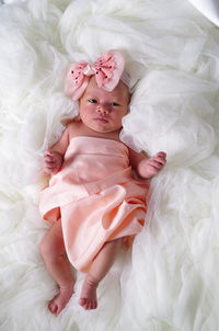 High angle portrait of cute baby girl lying on bed at home