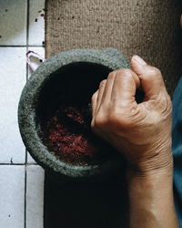 Cropped hand of person using mortar and pestle at home