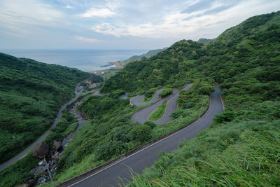 Scenic view of road by sea against sky