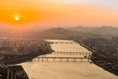 Bridge over river in city during sunset