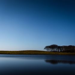 Scenic view of lake against clear blue sky