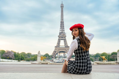 Young woman standing against cloudy sky