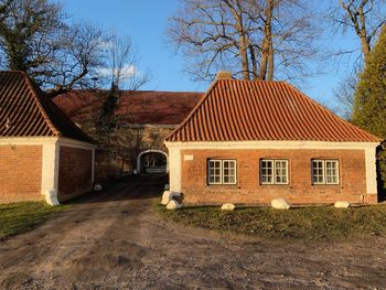 House amidst bare trees and buildings against sky