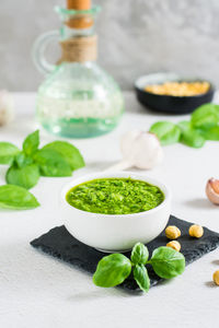 Fresh basil pesto sauce in a bowl on the table. homemade savory snacks. vertical view