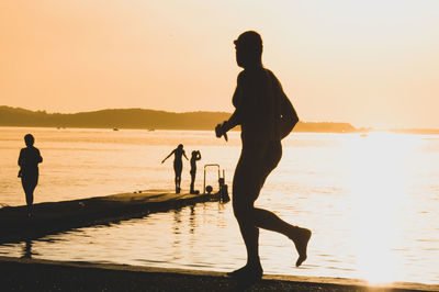 Side view of man running against sea during sunset