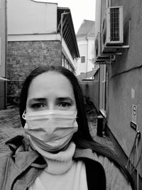 Portrait of woman wearing mask standing in alley