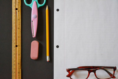 Directly above shot of reading glasses with stationary on table