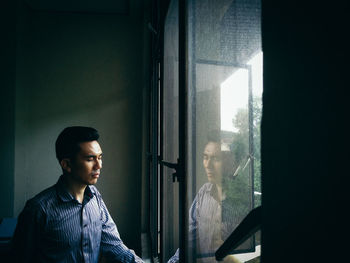 Man reflecting on glass window at home