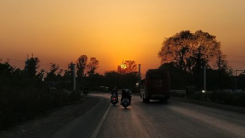 Cars on road against sky during sunset