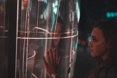 Woman by metal with reflection at night